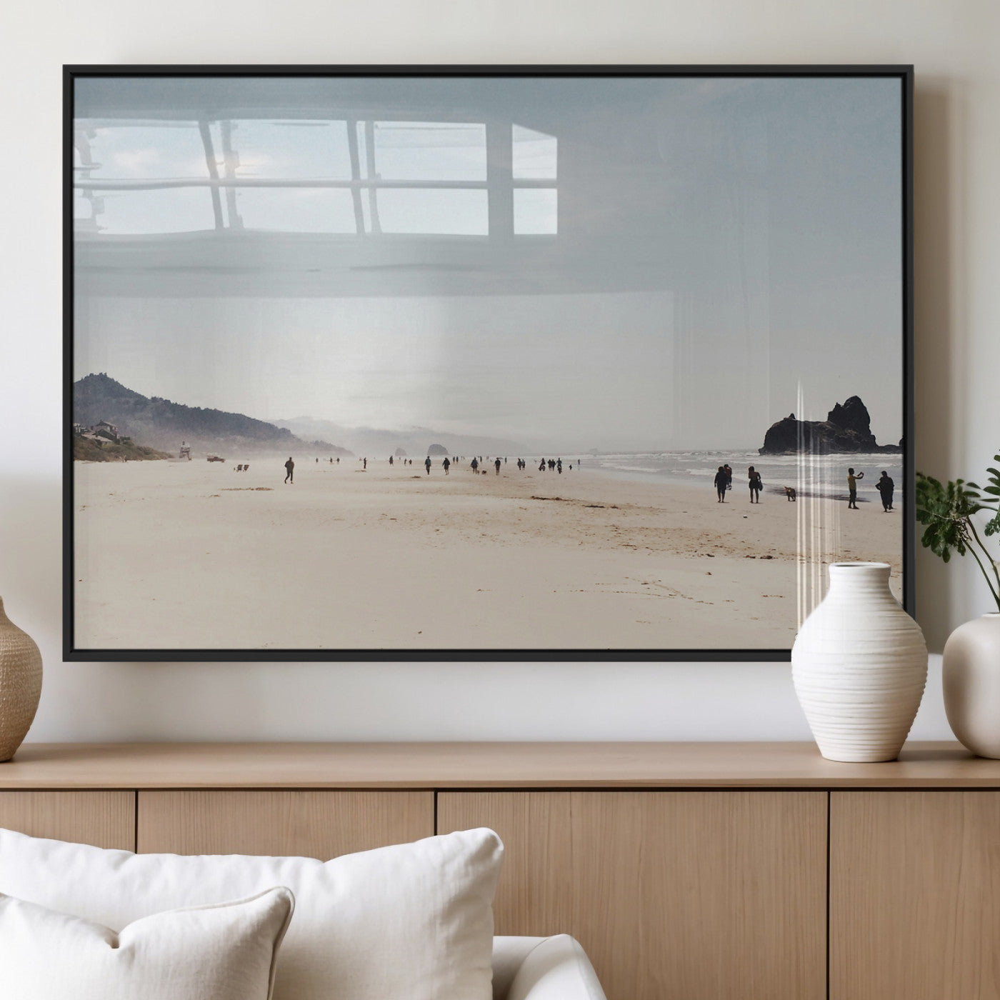 A serene beach with soft sand, misty mountains, and scattered people walking along the shoreline, creating a peaceful coastal landscape.