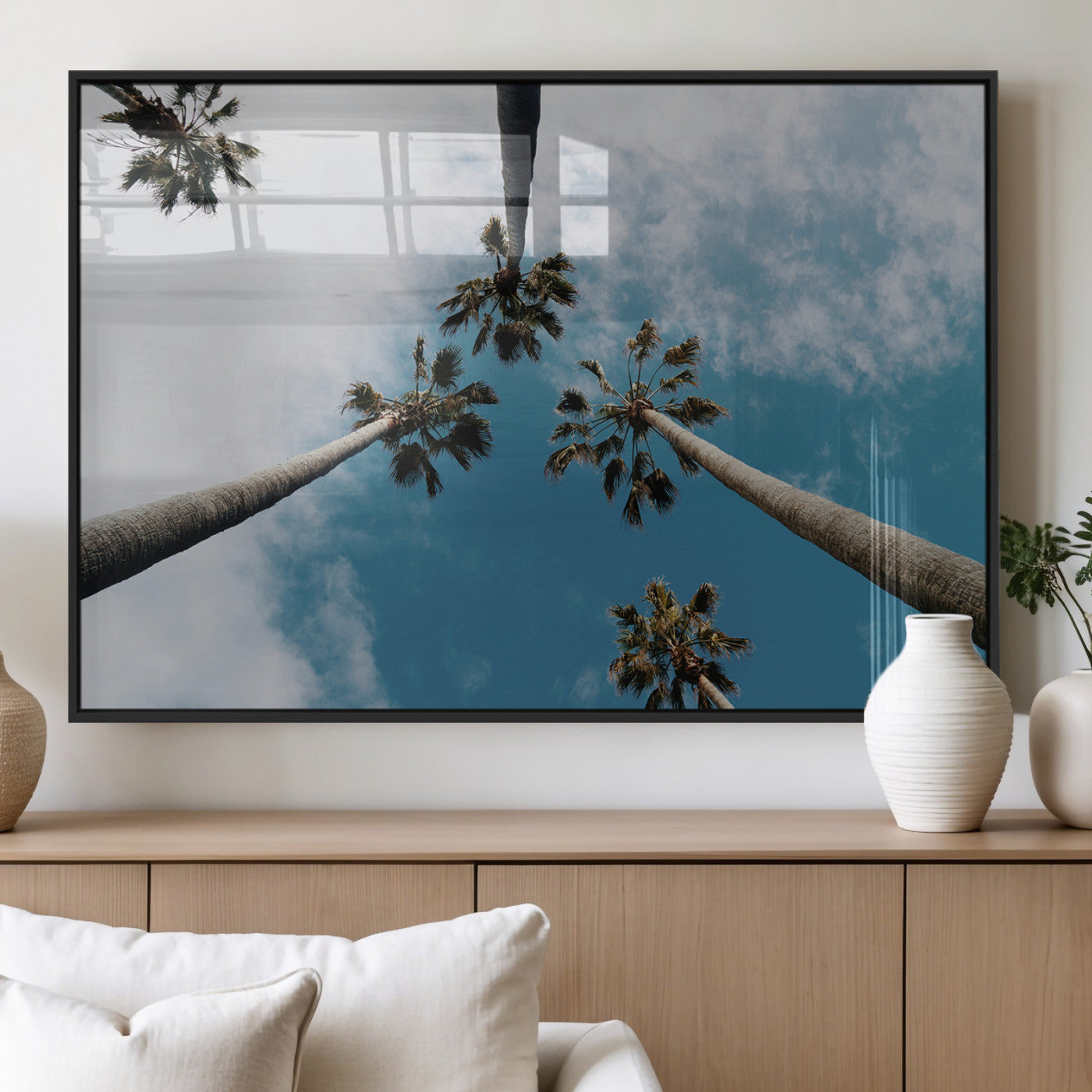 Looking up at tall palm trees against a bright blue sky with scattered clouds, creating a tropical and airy atmosphere for modern home decor.
