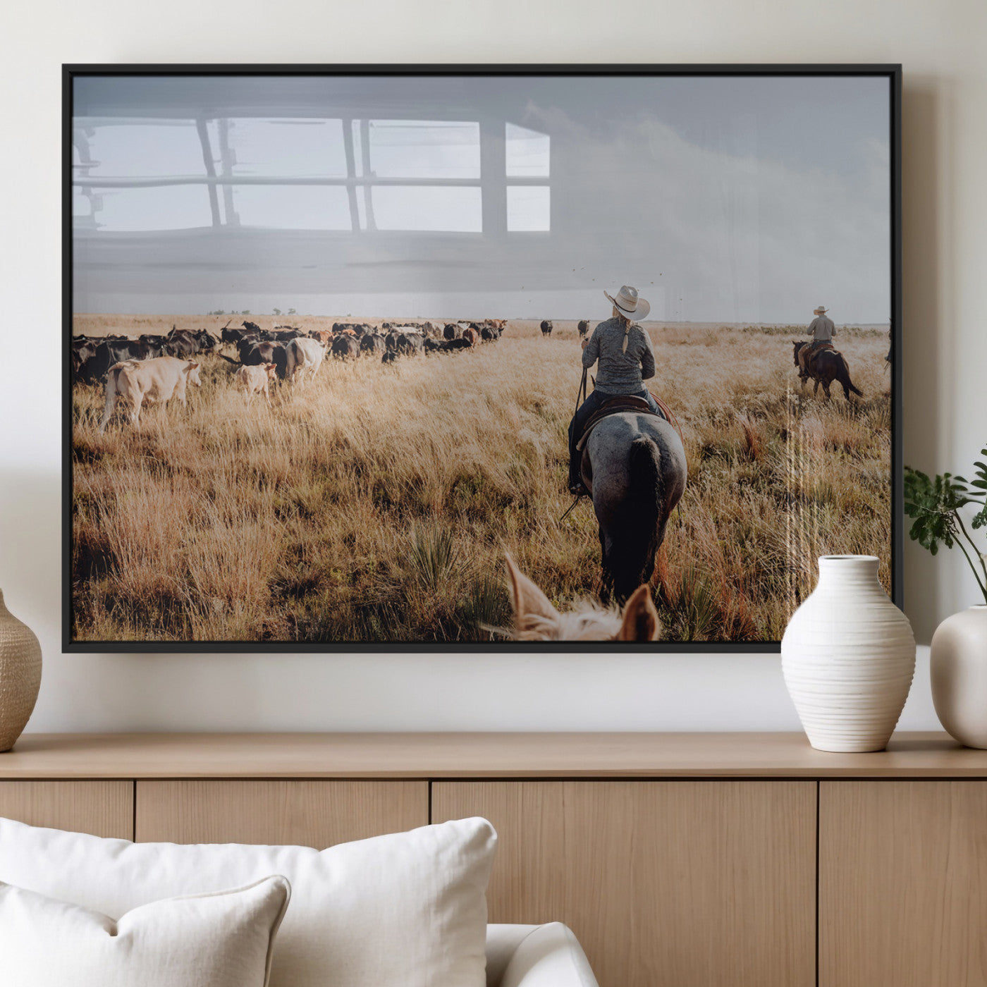 A cowboy and cowgirl on horseback herding cattle through golden grasslands, capturing a rustic and authentic Western ranch lifestyle.