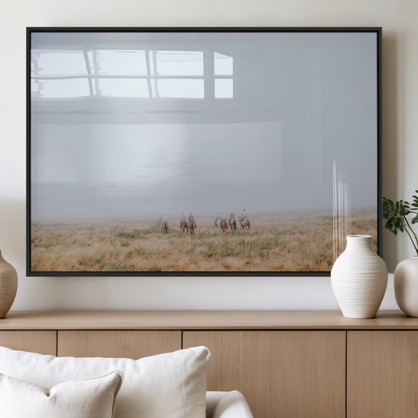 A group of horseback riders moving through a fog-shrouded field, evoking a calm Western scene with golden grasses and soft horizons.