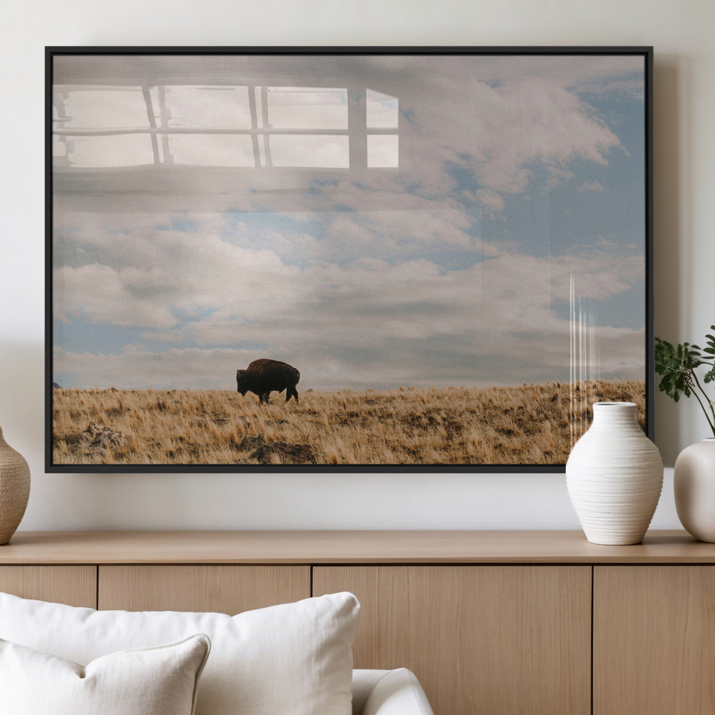 A solitary bison walking across a golden prairie under a vast, cloud-filled sky, evoking a peaceful, rustic western landscape for home decor.