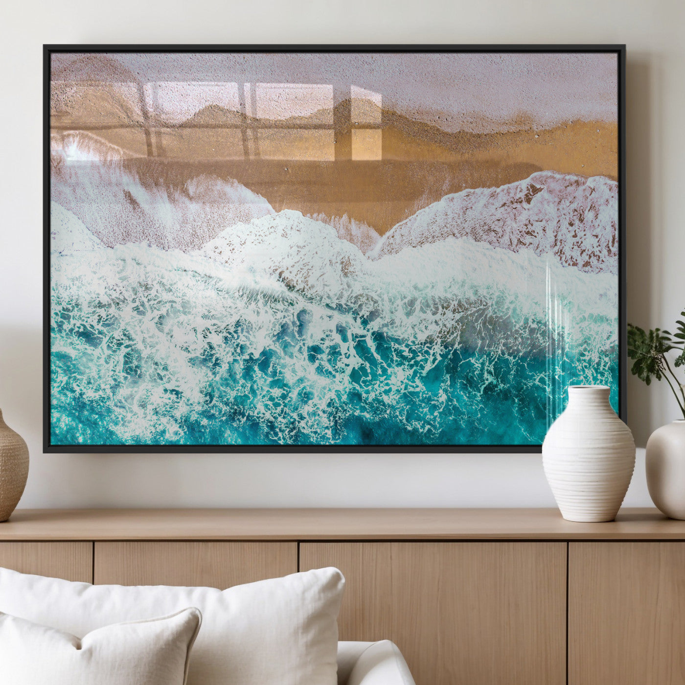 Aerial view of ocean waves crashing onto a sandy beach, with turquoise water and foamy white surf, creating a serene coastal aesthetic for home decor.