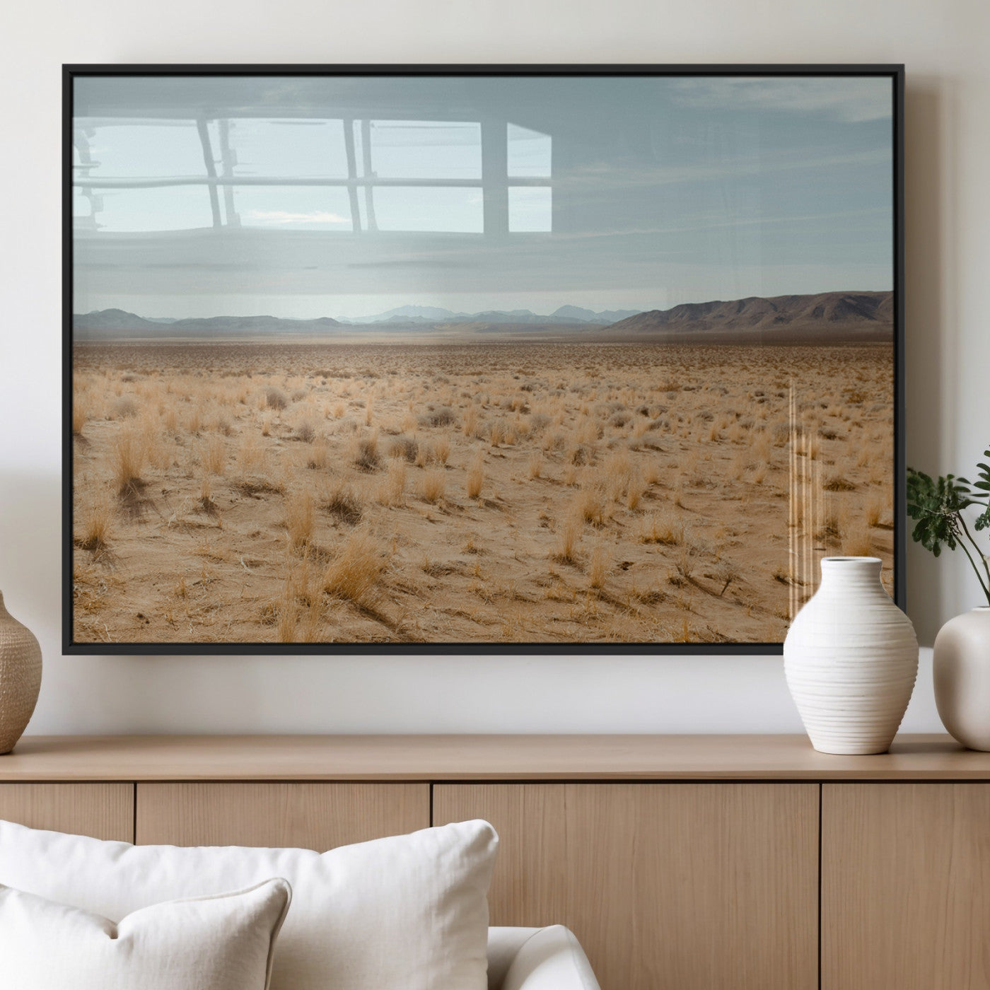 Expansive desert landscape with scattered dry grass and distant mountain range under a pale blue sky – Wall Art Canvas Print.