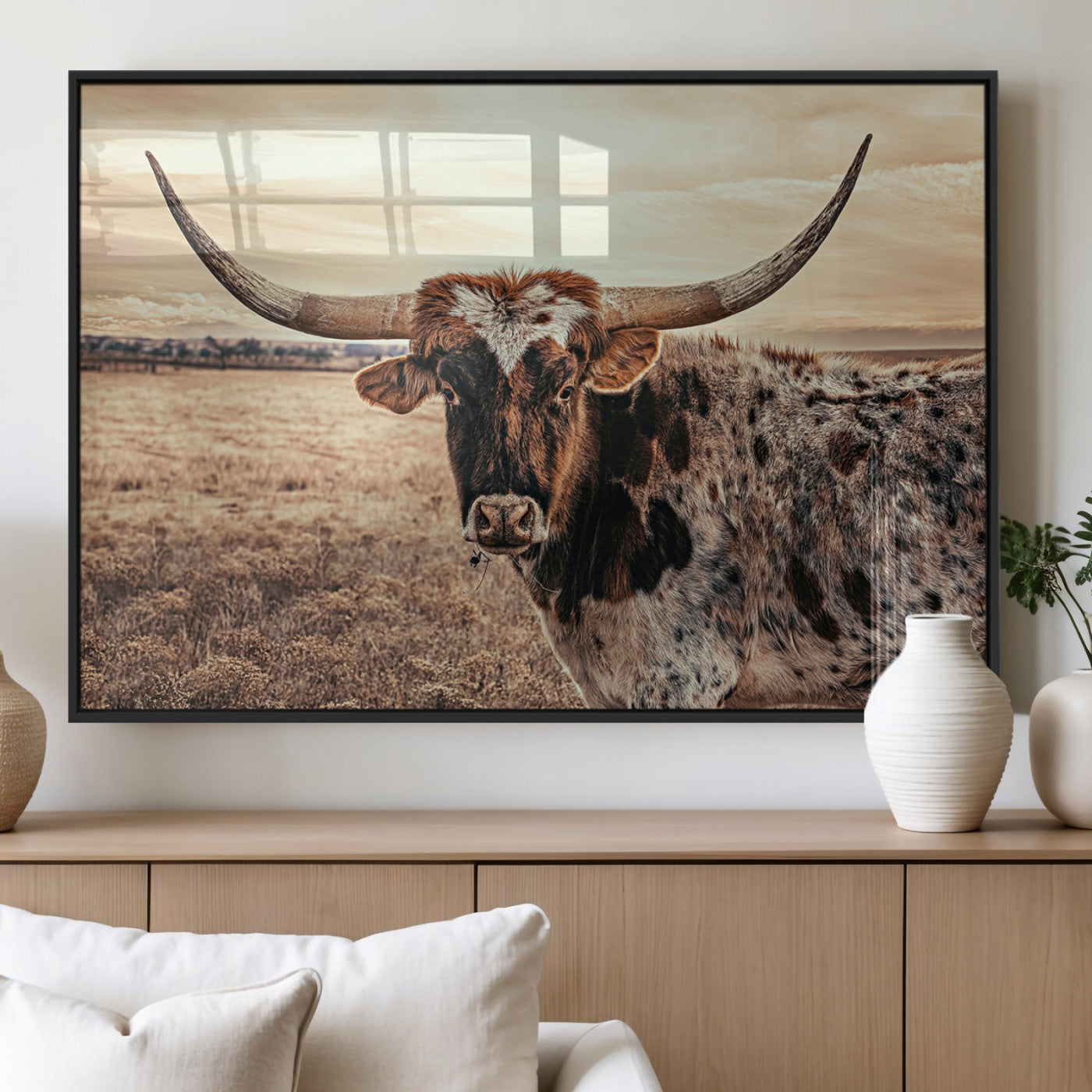 Close-up of a longhorn cow with distinctive curved horns standing in a dry grass field under a cloudy sky.