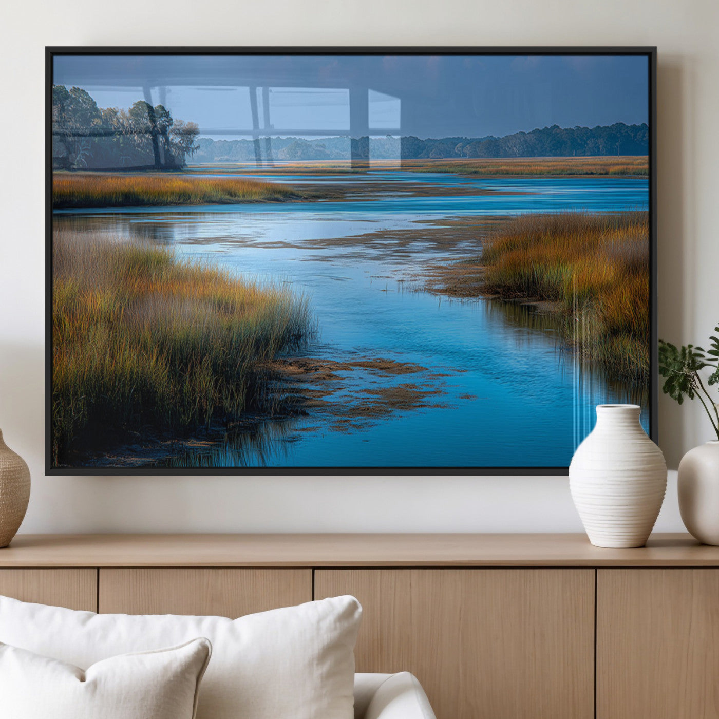 A peaceful marshland scene with calm blue water reflecting the surrounding grasses and trees, capturing the beauty of nature in a serene landscape.