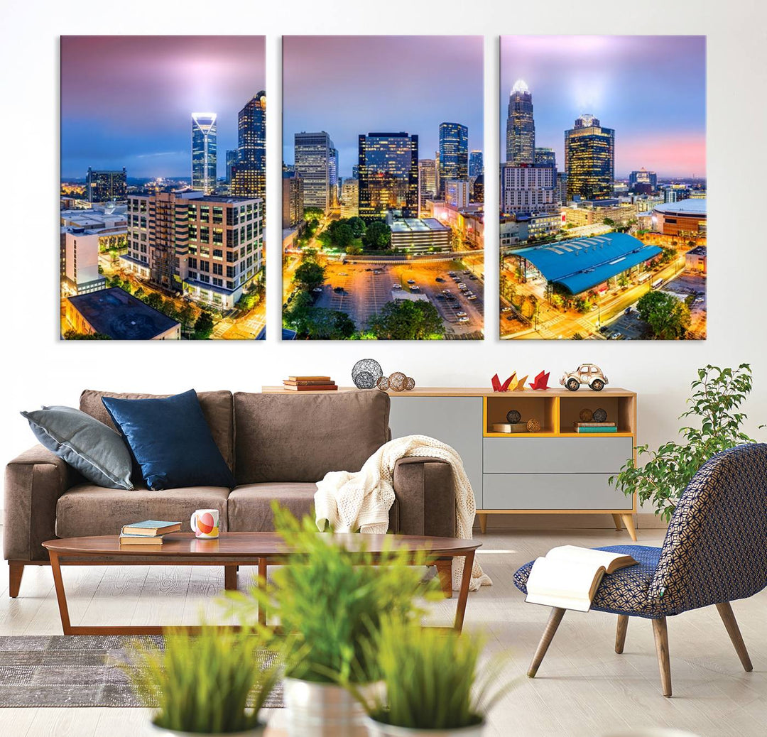 The living room features three large pieces of the *Charlotte City Lights Sunset Purple Skyline Cityscape View Wall Art Canvas Print*. Crafted on gallery-wrapped, museum-quality canvas with UV-protective coating, they grace the wall and add an artistic flair to the space.