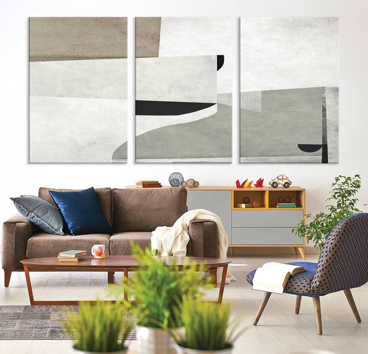 The Brown Gray Figures Abstract Wall Art Canvas Print is displayed as a triptych on a dark wall. The piece is gallery wrapped, offering a seamless finish and enhanced durability due to its UV-protective coating.