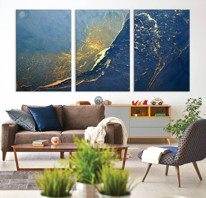 The Navy Blue Yellow Twinkle Wall Art Canvas Print, featuring an abstract design in gold and blue, enhances a modern living room as it adorns a white wall with its gallery-wrapped, museum-quality canvases for an exquisite touch.