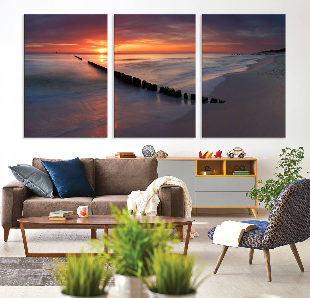 In a modern living room, the Sunset Beach Wall Art Canvas Print is displayed above. This triptych, printed on museum-quality canvas with a UV-protective coating, ensures lasting brilliance. It's ready to hang and brings an elegant touch to your space.