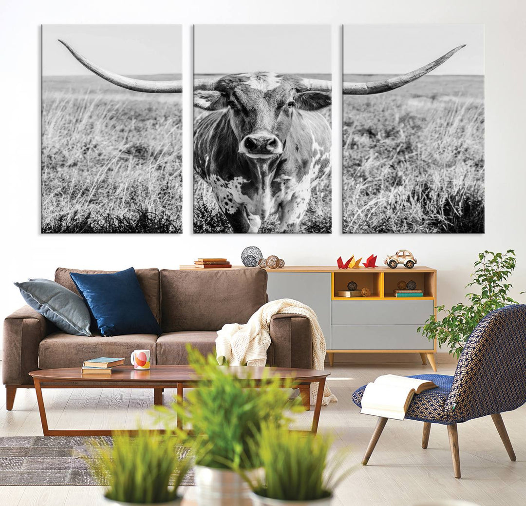 The Texas Cow Longhorn Wall Art Canvas Print is a black and white triptych depicting a cow in a field. It is crafted with museum-quality canvas and features a UV-protective coating.