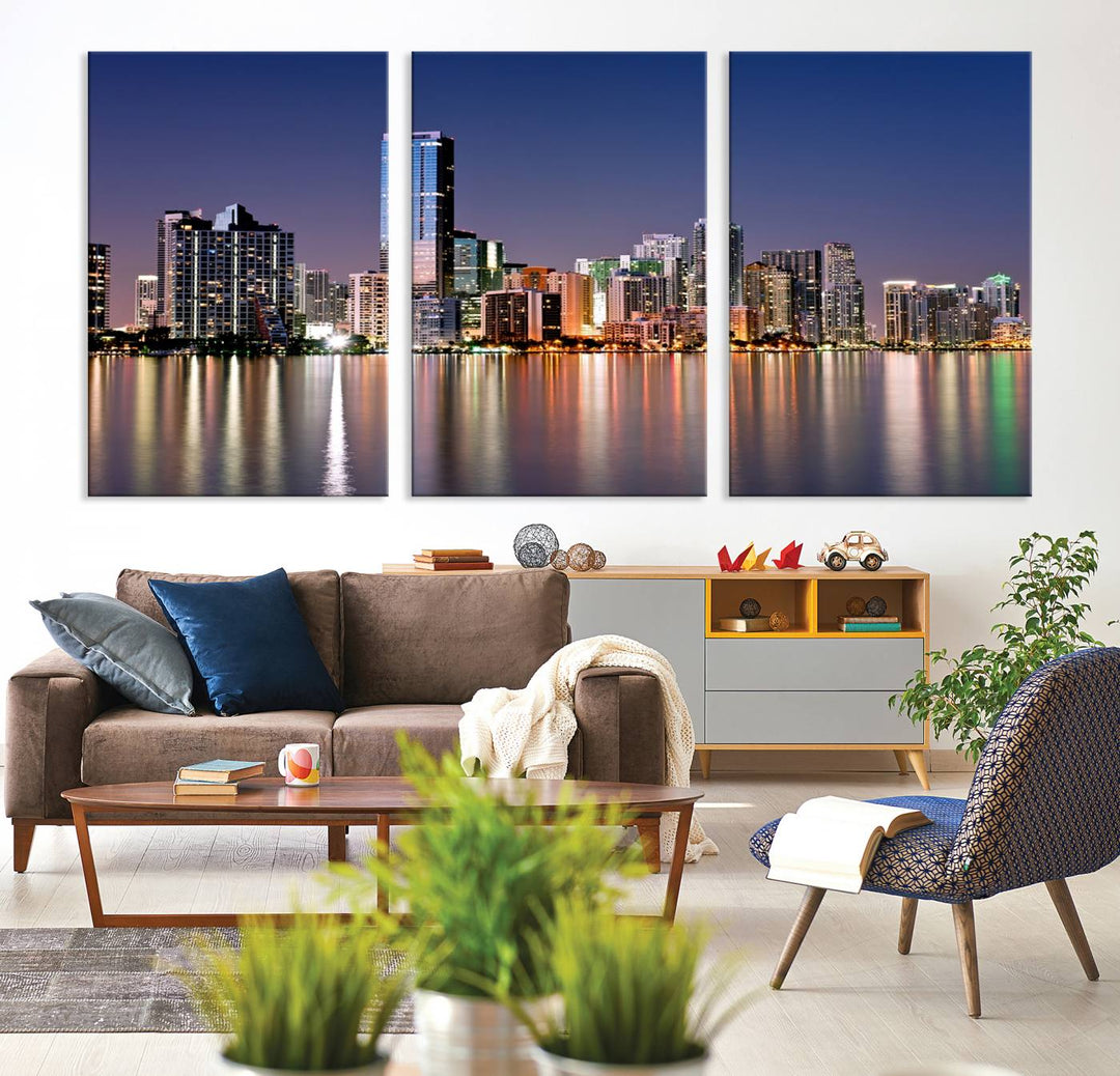 The Miami Skyline Canvas Wall Art Print showcases a vibrant night cityscape and beautifully captures the dazzling colorful lights reflecting on the water. This ready-to-hang triptych adorns the wall, creating a stunning visual centerpiece.