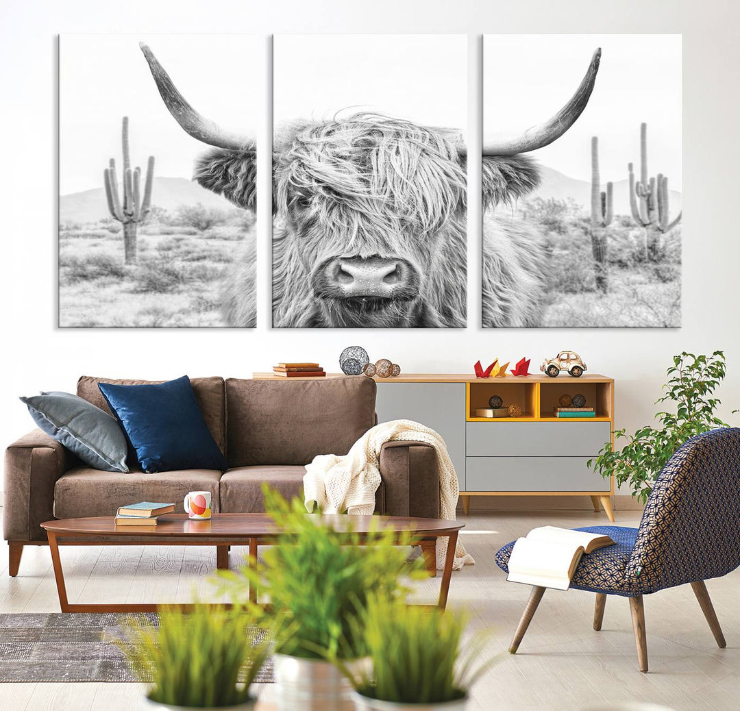 The "Rustic Charm | Cow Longhorn Black White Bighorn Wall Art Canvas Print" is a stunning triptych that showcases a highland cow with long horns set against a desert landscape with cacti in the background. This farmhouse wall art elevates any room into a rustic haven with its gallery-quality canvas.