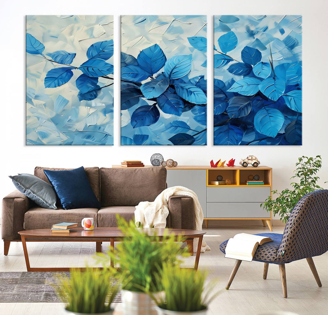 The contemporary living room is highlighted by the Abstract Blue Leaf Wall Art Canvas Print on the wall. The hand-assembled framed art enhances the room's vibrant decor, crafting a gallery-worthy ambience.