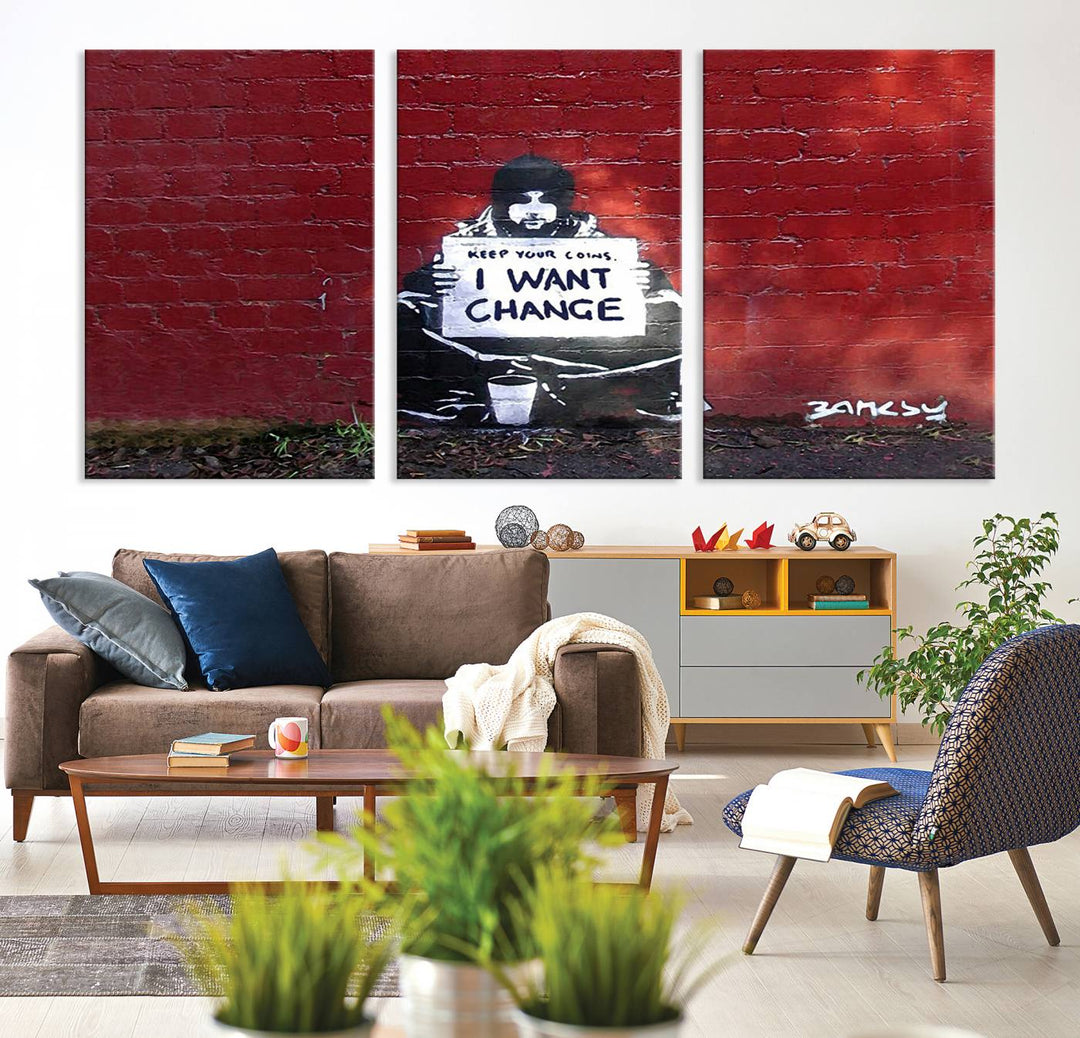 The living room showcases a triptych of stencil artwork on museum-quality canvas, featuring the Banksy I Want Change Graffiti Abstract Wall Art Canvas Print. This captivating piece depicts a person holding a sign that says "I want change" and is finished with a UV-protective coating to ensure long-lasting beauty.