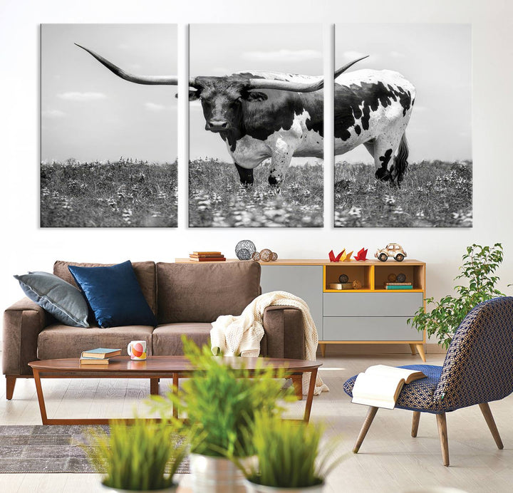 The Texas Black White Highland Longhorn Cow Wall Art Canvas Print, a gallery-quality triptych, elegantly adorns the wall, showcasing a striking black-and-white depiction of a longhorn cow in a field.