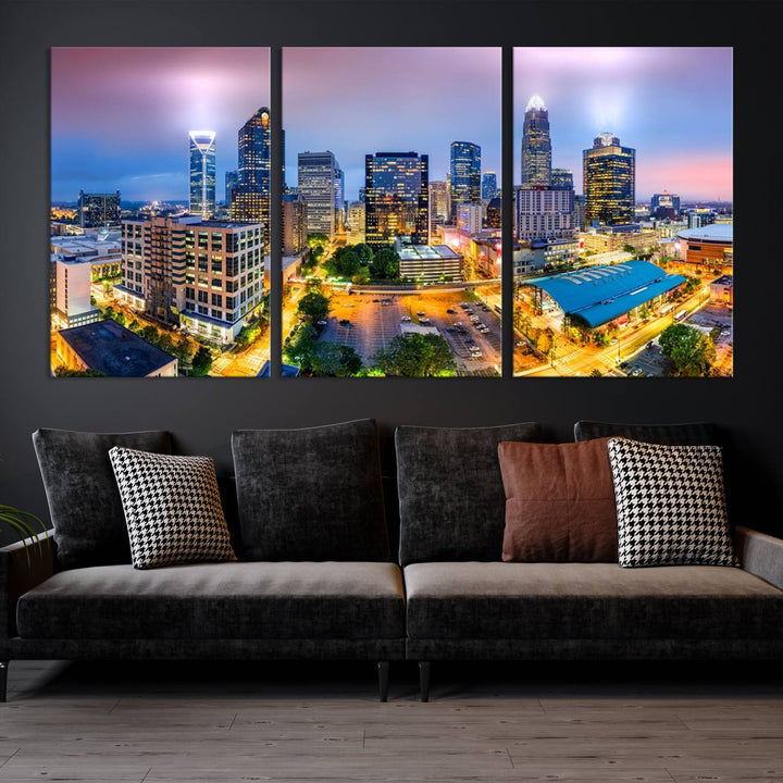 The living room features three large pieces of the *Charlotte City Lights Sunset Purple Skyline Cityscape View Wall Art Canvas Print*. Crafted on gallery-wrapped, museum-quality canvas with UV-protective coating, they grace the wall and add an artistic flair to the space.