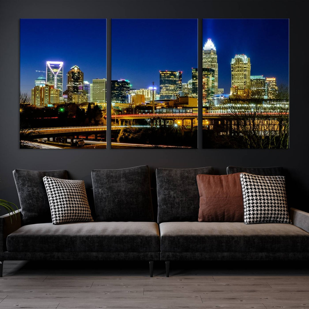 The Charlotte City Lights Night Blue Skyline Cityscape View Wall Art Canvas Print, showcasing an illuminated city skyline at night, is printed on museum-quality canvas with a UV-protective coating. Enhance your space with this stunning piece and enjoy free shipping with your purchase.