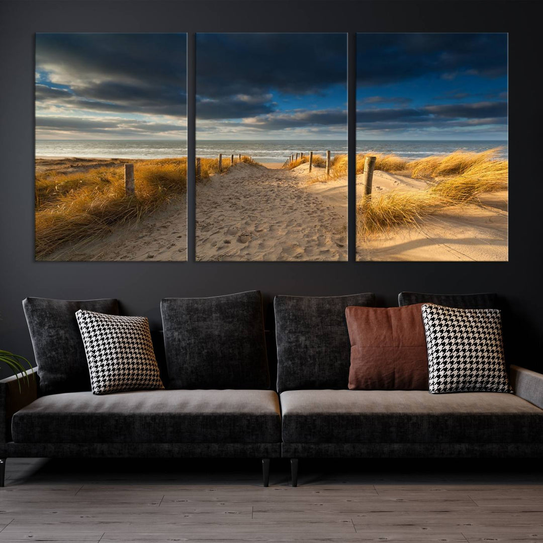 The Ocean Beach Dark Clouds Wall Art Canvas Print is a breathtaking triptych depicting a sandy beach path with tall grasses under an intense cloudy sky. It is crafted on museum-quality canvas with UV protection.