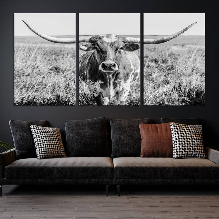 The Texas Cow Longhorn Wall Art Canvas Print is a black and white triptych depicting a cow in a field. It is crafted with museum-quality canvas and features a UV-protective coating.