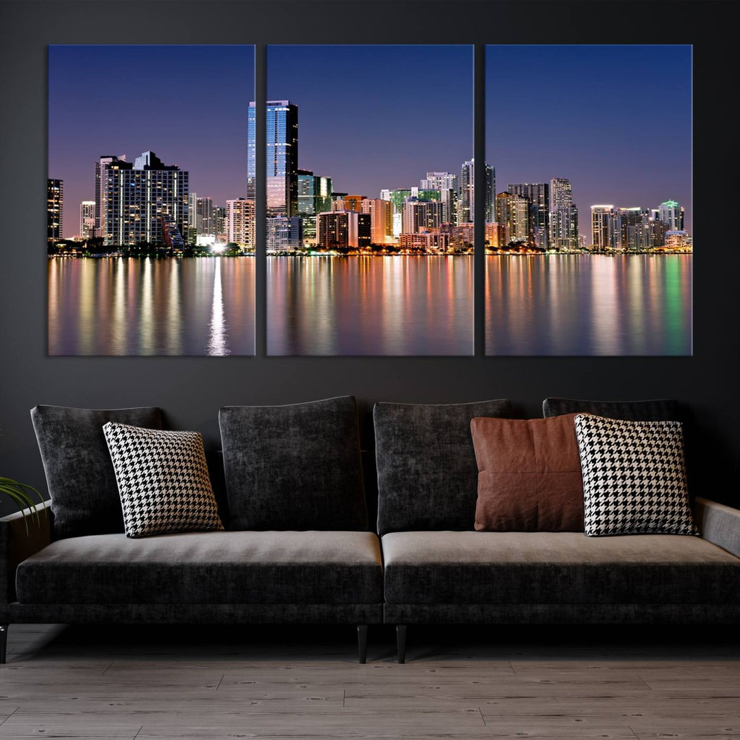 The Miami Skyline Canvas Wall Art Print showcases a vibrant night cityscape and beautifully captures the dazzling colorful lights reflecting on the water. This ready-to-hang triptych adorns the wall, creating a stunning visual centerpiece.