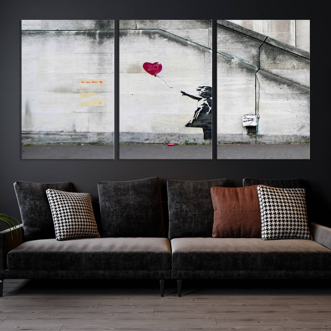 The "Girl with a Balloon Banksy Street Graffiti Art Canvas Print" is a gallery-quality wall art piece that features an image of a girl releasing a heart-shaped balloon. Handmade in the USA, this canvas artwork brings charm and emotion to any room.