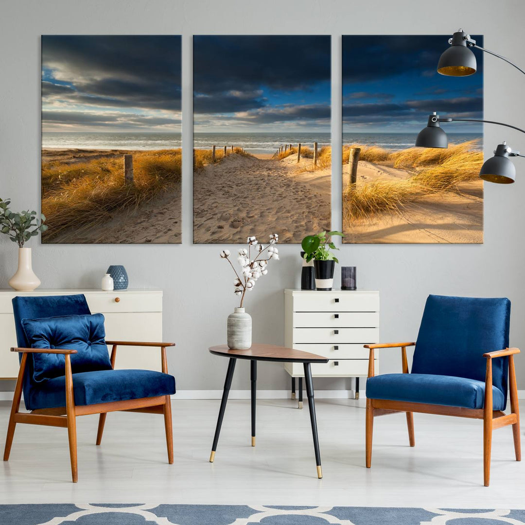 The Ocean Beach Dark Clouds Wall Art Canvas Print is a breathtaking triptych depicting a sandy beach path with tall grasses under an intense cloudy sky. It is crafted on museum-quality canvas with UV protection.