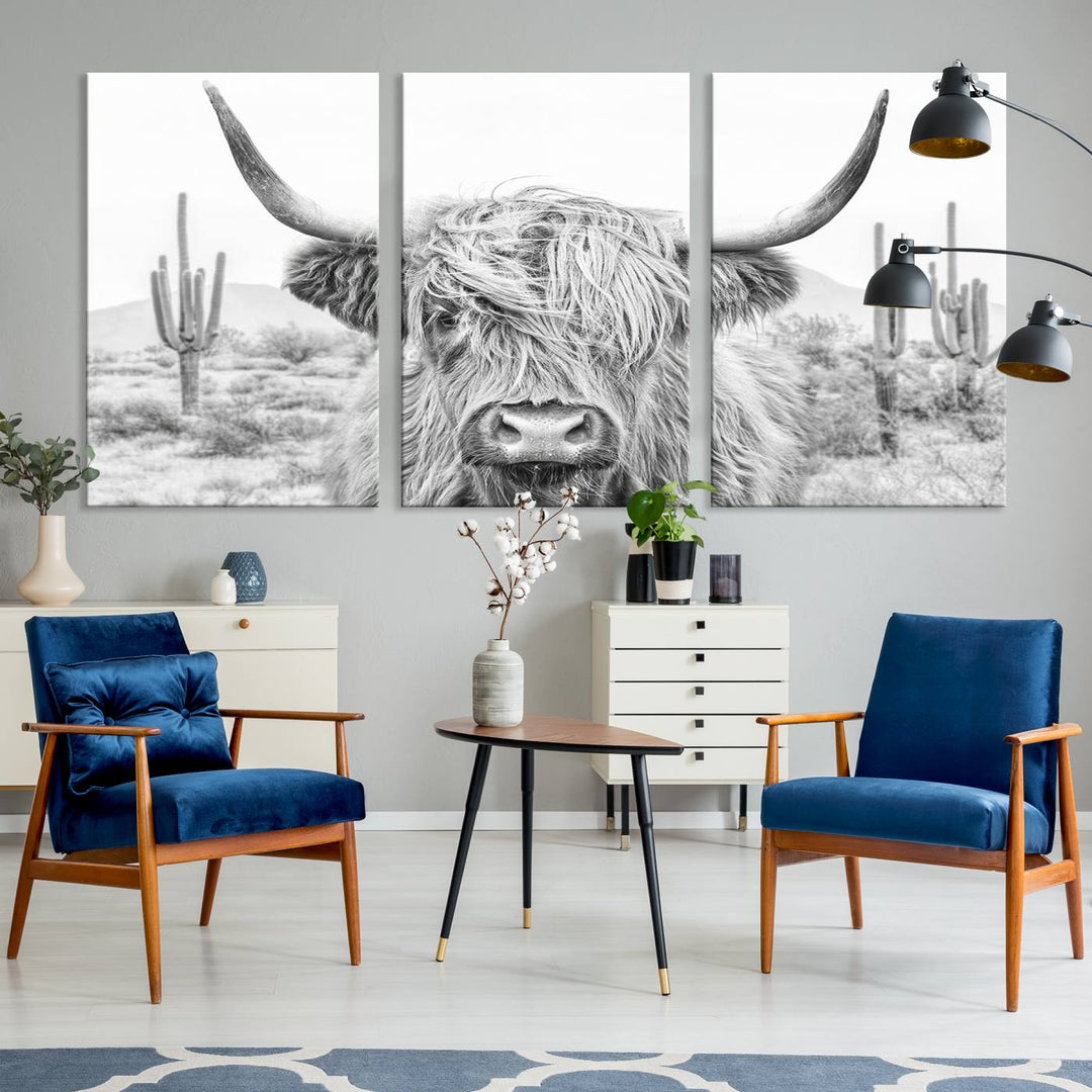 The "Rustic Charm | Cow Longhorn Black White Bighorn Wall Art Canvas Print" is a stunning triptych that showcases a highland cow with long horns set against a desert landscape with cacti in the background. This farmhouse wall art elevates any room into a rustic haven with its gallery-quality canvas.