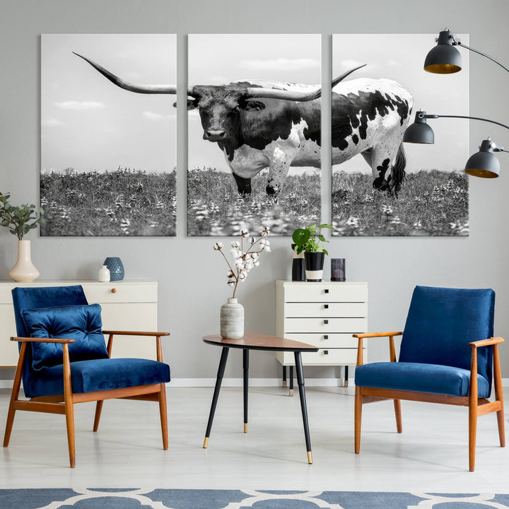 The Texas Black White Highland Longhorn Cow Wall Art Canvas Print, a gallery-quality triptych, elegantly adorns the wall, showcasing a striking black-and-white depiction of a longhorn cow in a field.