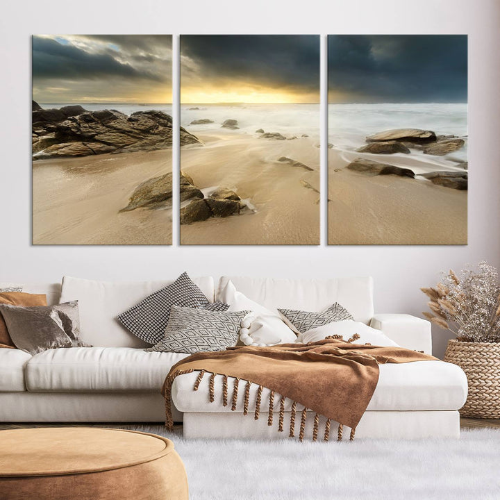 A gallery-wrapped, three-panel artwork titled "Rocks and Waves Wall Art Canvas Print" depicts a rocky beach at sunset. Each canvas showcases museum-quality craftsmanship and a UV-protective coating to maintain its vibrant colors.