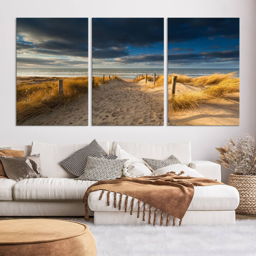 The Ocean Beach Dark Clouds Wall Art Canvas Print is a breathtaking triptych depicting a sandy beach path with tall grasses under an intense cloudy sky. It is crafted on museum-quality canvas with UV protection.