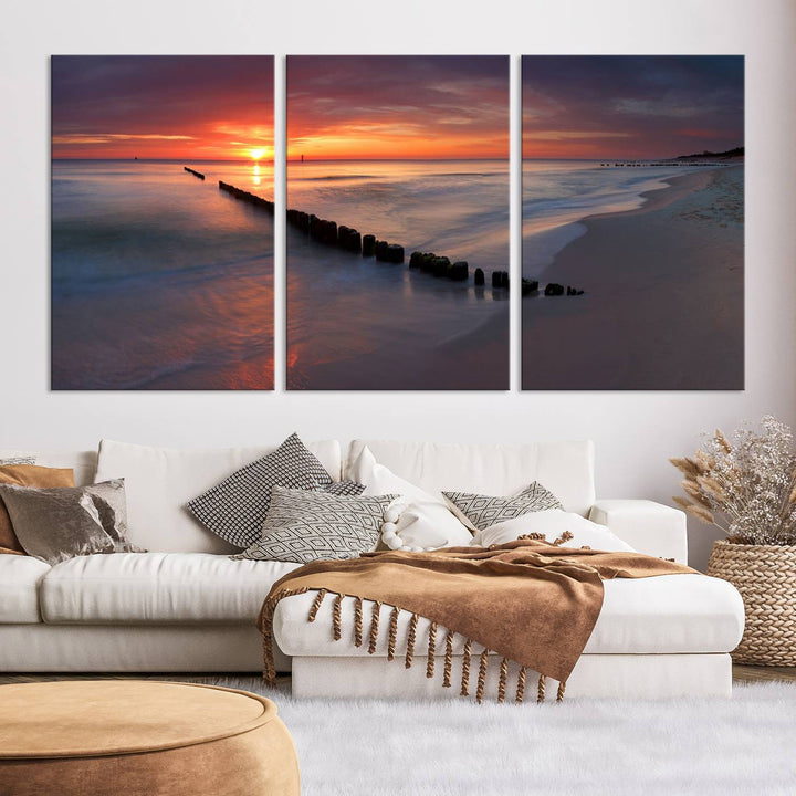 In a modern living room, the Sunset Beach Wall Art Canvas Print is displayed above. This triptych, printed on museum-quality canvas with a UV-protective coating, ensures lasting brilliance. It's ready to hang and brings an elegant touch to your space.