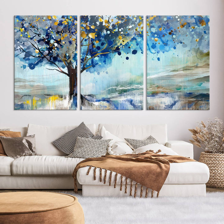 A modern living room features a three-panel Watercolor Style Abstract Tree Printing Wall Art Canvas in vibrant blue and yellow, crafted on museum-quality material.