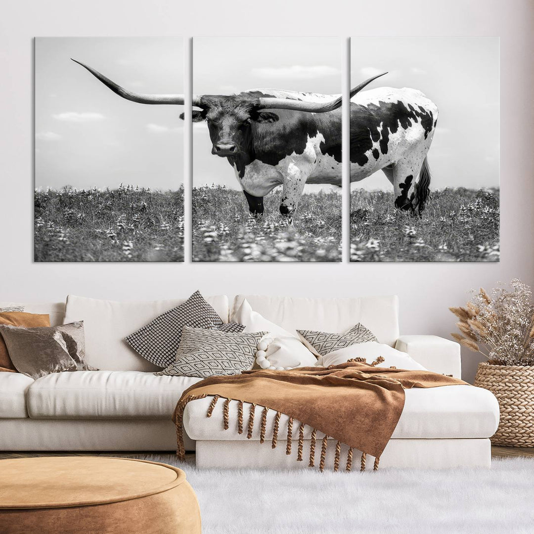 The Texas Black White Highland Longhorn Cow Wall Art Canvas Print, a gallery-quality triptych, elegantly adorns the wall, showcasing a striking black-and-white depiction of a longhorn cow in a field.