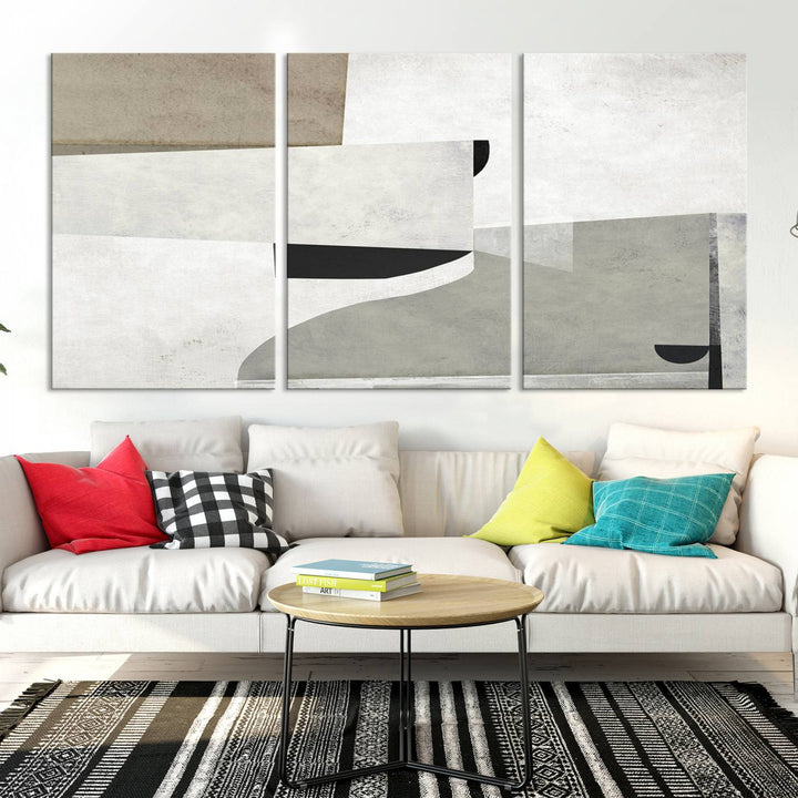 The Brown Gray Figures Abstract Wall Art Canvas Print is displayed as a triptych on a dark wall. The piece is gallery wrapped, offering a seamless finish and enhanced durability due to its UV-protective coating.