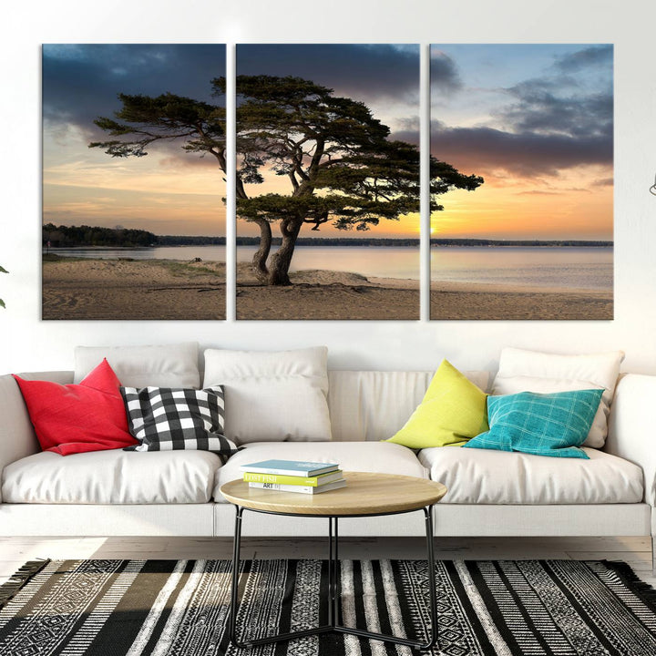 The room showcases the Coastal Sunset Wall Art Canvas Print, a triptych elegantly displayed on museum-quality polycotton canvas, depicting a serene beach sunset with a tree.