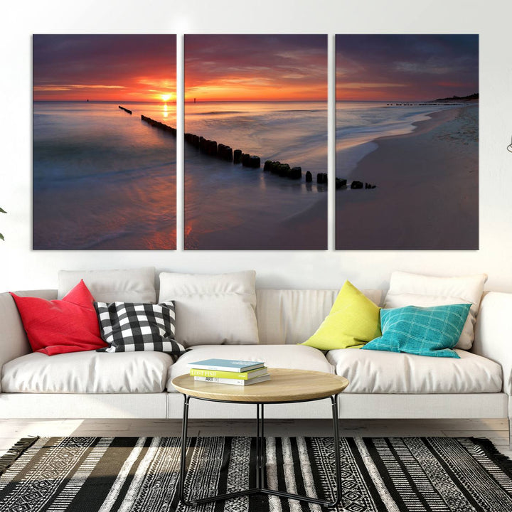 In a modern living room, the Sunset Beach Wall Art Canvas Print is displayed above. This triptych, printed on museum-quality canvas with a UV-protective coating, ensures lasting brilliance. It's ready to hang and brings an elegant touch to your space.