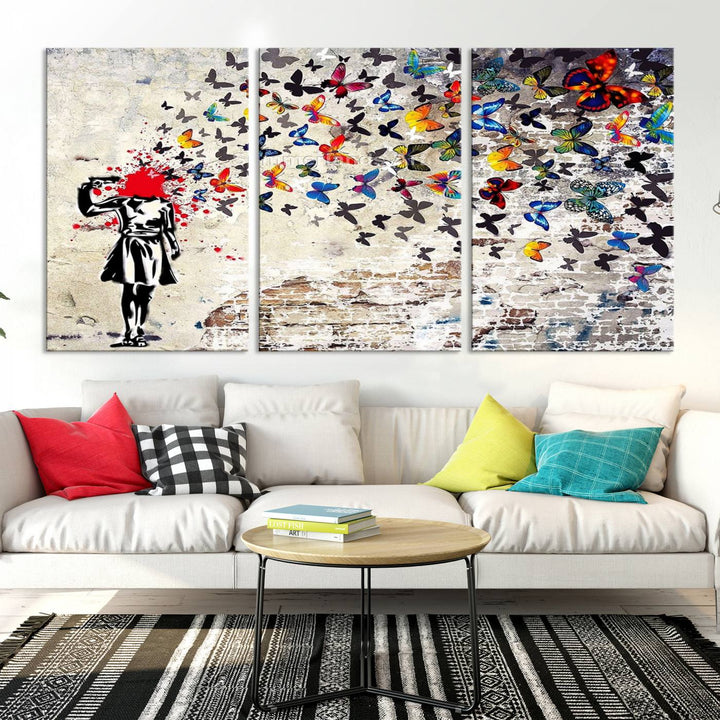 The Banksy Art Butterfly Girl Explosion Canvas showcases a dynamic figure with butterflies bursting from their head, set against a textured wall background. This vibrant urban graffiti piece is perfect for modern interiors and comes ready to hang.