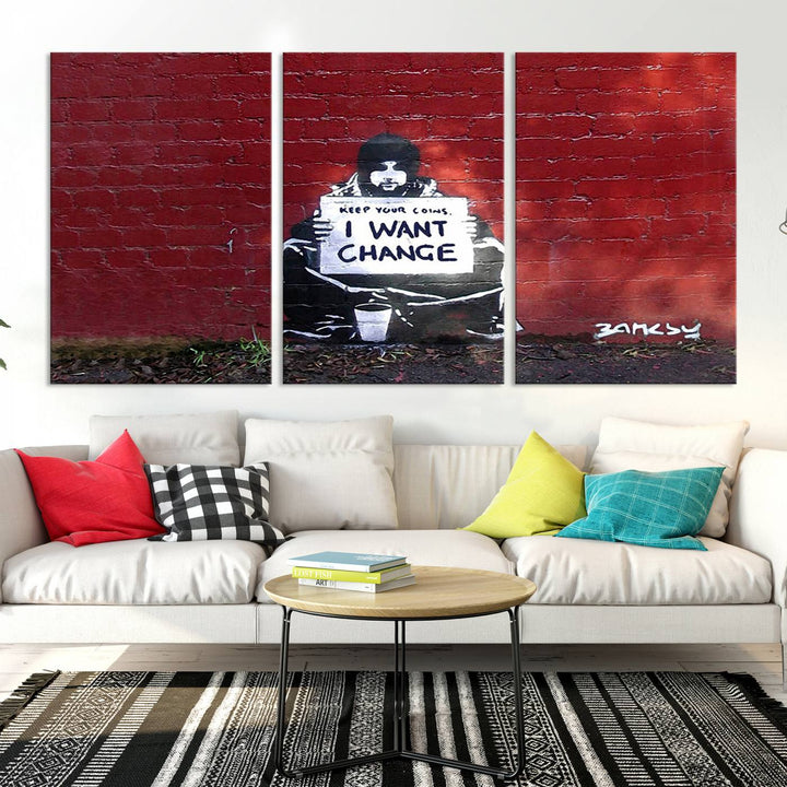 The living room showcases a triptych of stencil artwork on museum-quality canvas, featuring the Banksy I Want Change Graffiti Abstract Wall Art Canvas Print. This captivating piece depicts a person holding a sign that says "I want change" and is finished with a UV-protective coating to ensure long-lasting beauty.