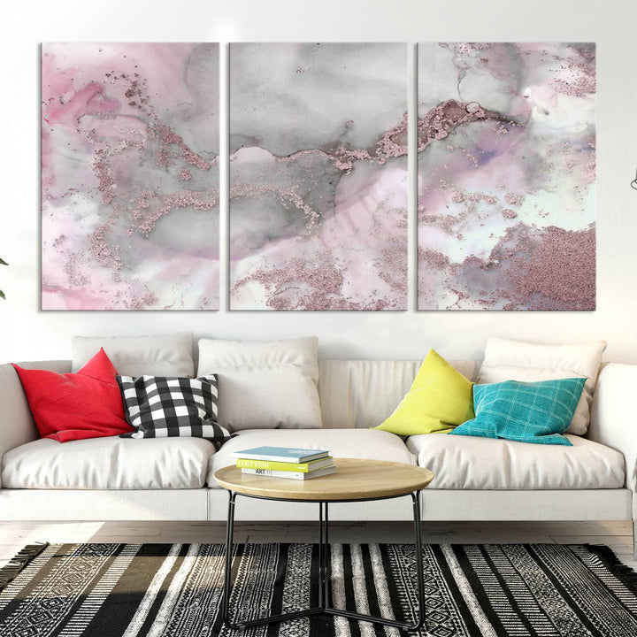 The Rose Marble Abstract Wall Art Canvas Print is a stunning triptych that showcases pink and gray tones, elegantly presented on a dark wall.