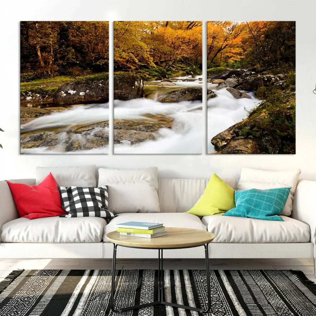 The living room is adorned with the "Wall Art Waterfall Canvas Print River in Forest in Autumn," a triptych on museum-quality canvas showcasing a flowing river surrounded by autumn trees. This ready-to-hang artwork features a UV-protective coating to ensure enduring vibrancy.