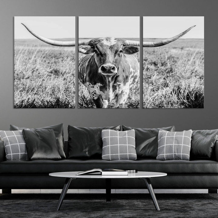 The Texas Cow Longhorn Wall Art Canvas Print is a black and white triptych depicting a cow in a field. It is crafted with museum-quality canvas and features a UV-protective coating.