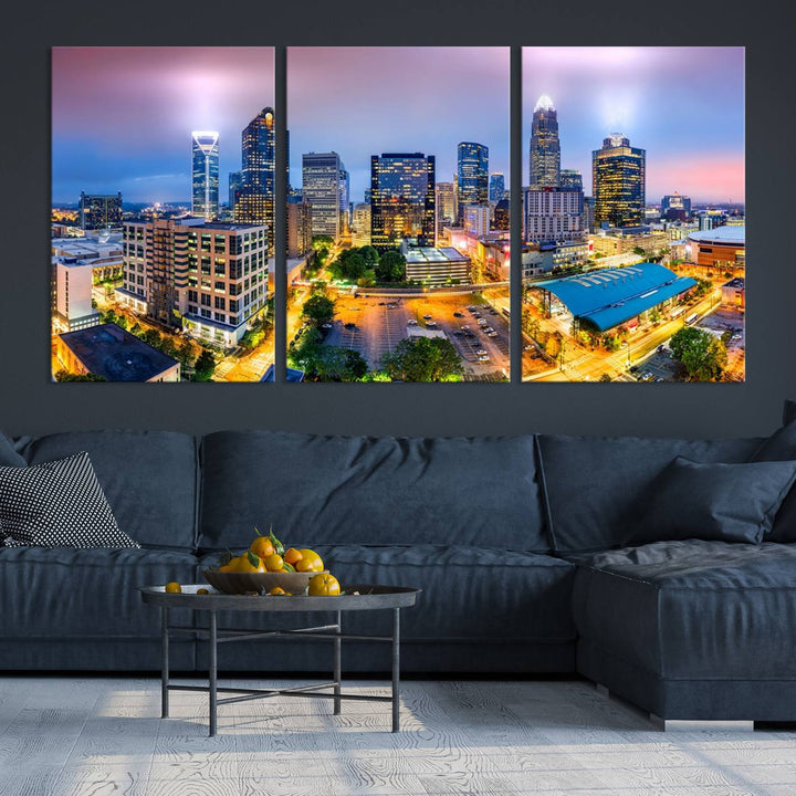 The living room features three large pieces of the *Charlotte City Lights Sunset Purple Skyline Cityscape View Wall Art Canvas Print*. Crafted on gallery-wrapped, museum-quality canvas with UV-protective coating, they grace the wall and add an artistic flair to the space.