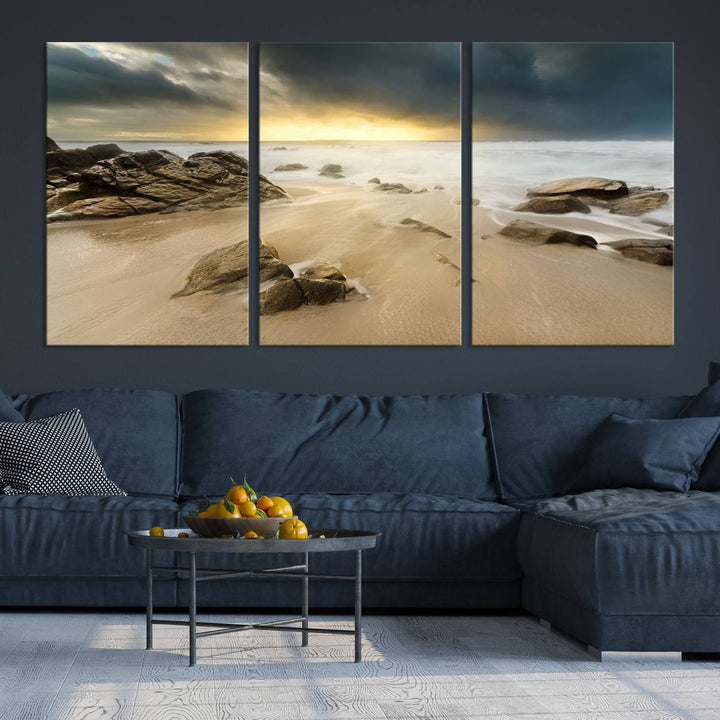 A gallery-wrapped, three-panel artwork titled "Rocks and Waves Wall Art Canvas Print" depicts a rocky beach at sunset. Each canvas showcases museum-quality craftsmanship and a UV-protective coating to maintain its vibrant colors.