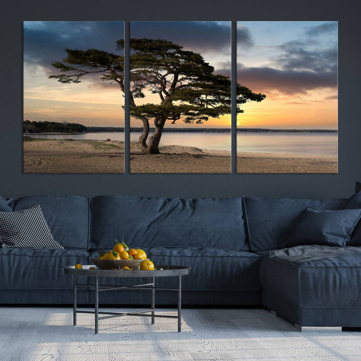 The room showcases the Coastal Sunset Wall Art Canvas Print, a triptych elegantly displayed on museum-quality polycotton canvas, depicting a serene beach sunset with a tree.