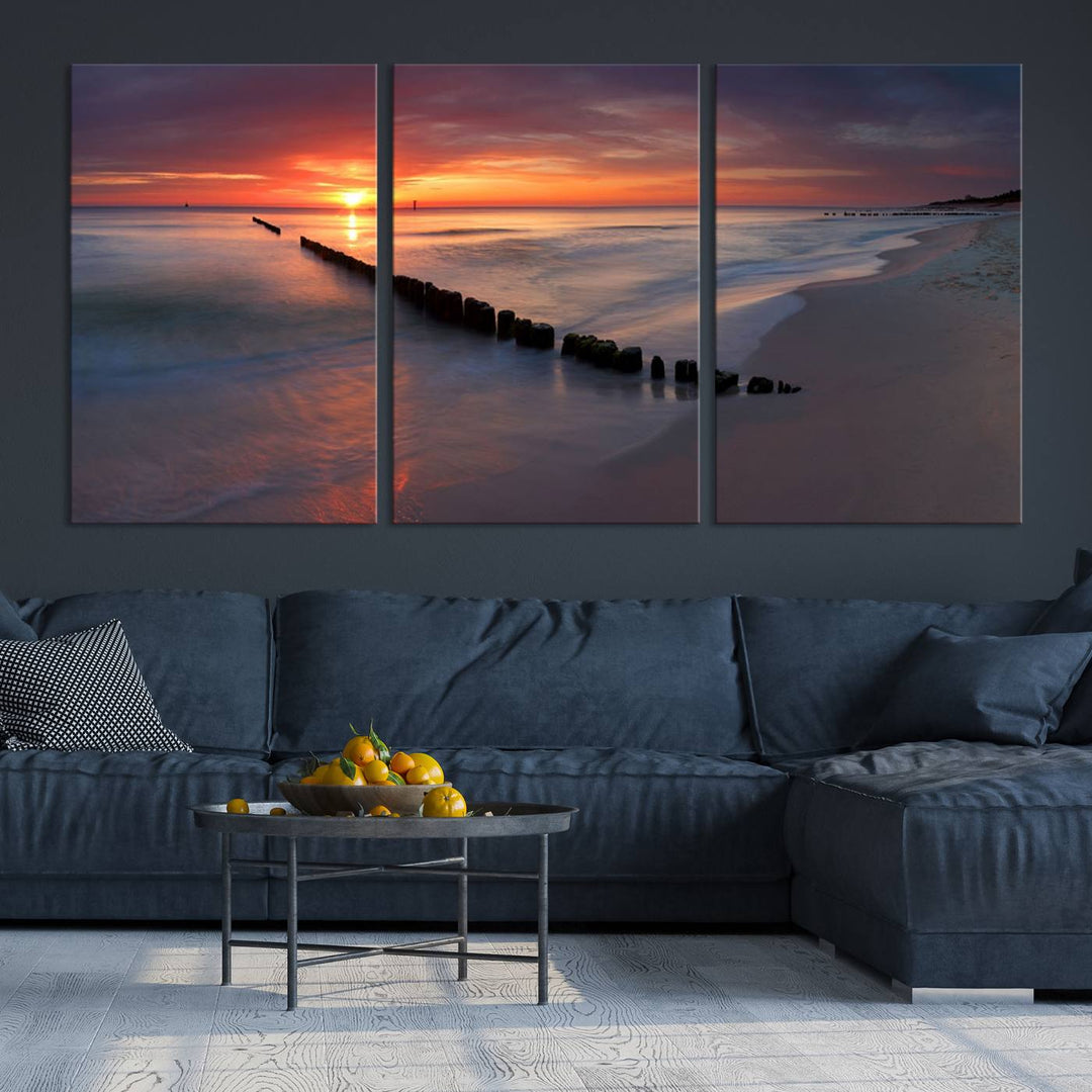 In a modern living room, the Sunset Beach Wall Art Canvas Print is displayed above. This triptych, printed on museum-quality canvas with a UV-protective coating, ensures lasting brilliance. It's ready to hang and brings an elegant touch to your space.