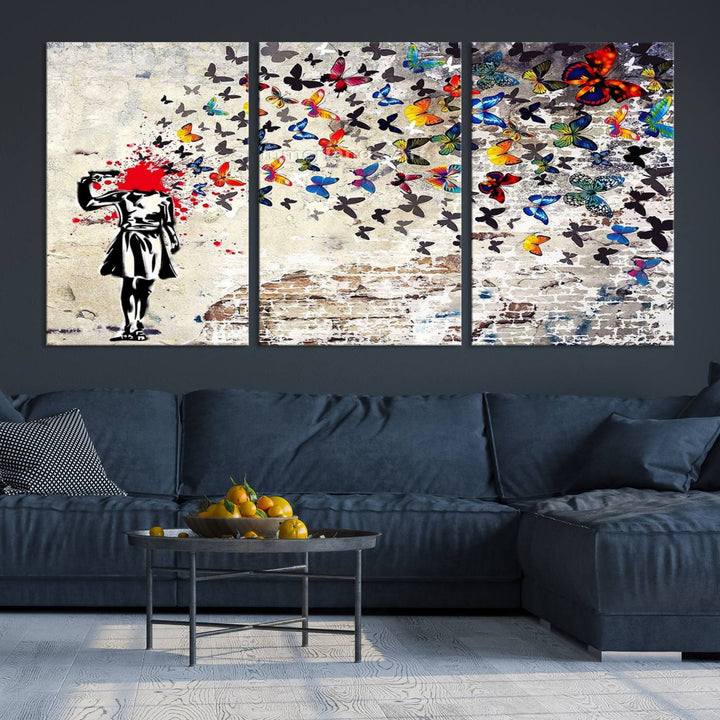 The Banksy Art Butterfly Girl Explosion Canvas showcases a dynamic figure with butterflies bursting from their head, set against a textured wall background. This vibrant urban graffiti piece is perfect for modern interiors and comes ready to hang.