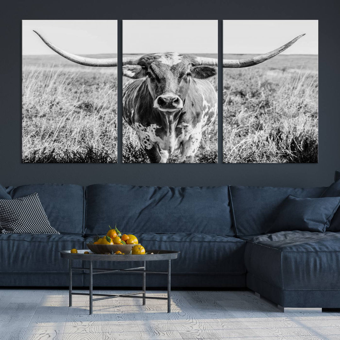 The Texas Cow Longhorn Wall Art Canvas Print is a black and white triptych depicting a cow in a field. It is crafted with museum-quality canvas and features a UV-protective coating.