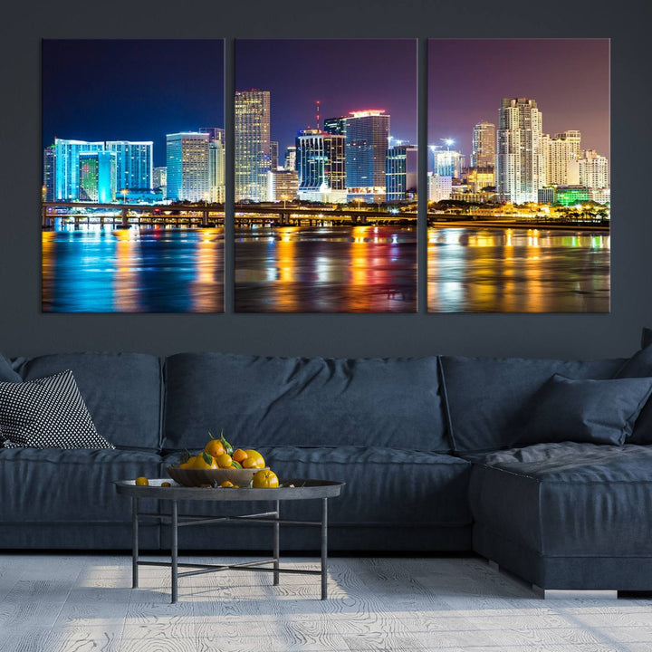 The Wall Art MIAMI Canvas Print features a stunning triptych of a city skyline at night, with vibrant lights reflecting on the water. This gallery-wrapped piece on museum-quality canvas delivers an exquisite finish.