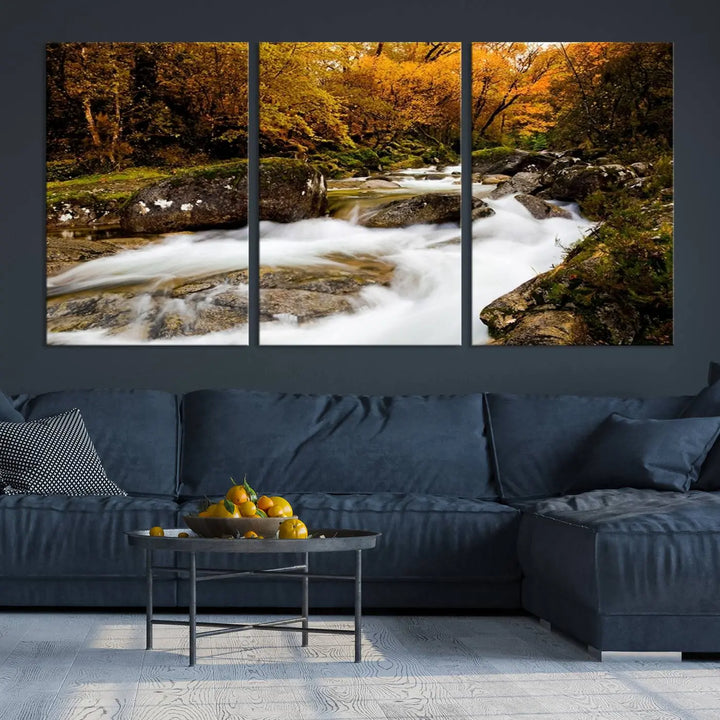 The living room is adorned with the "Wall Art Waterfall Canvas Print River in Forest in Autumn," a triptych on museum-quality canvas showcasing a flowing river surrounded by autumn trees. This ready-to-hang artwork features a UV-protective coating to ensure enduring vibrancy.