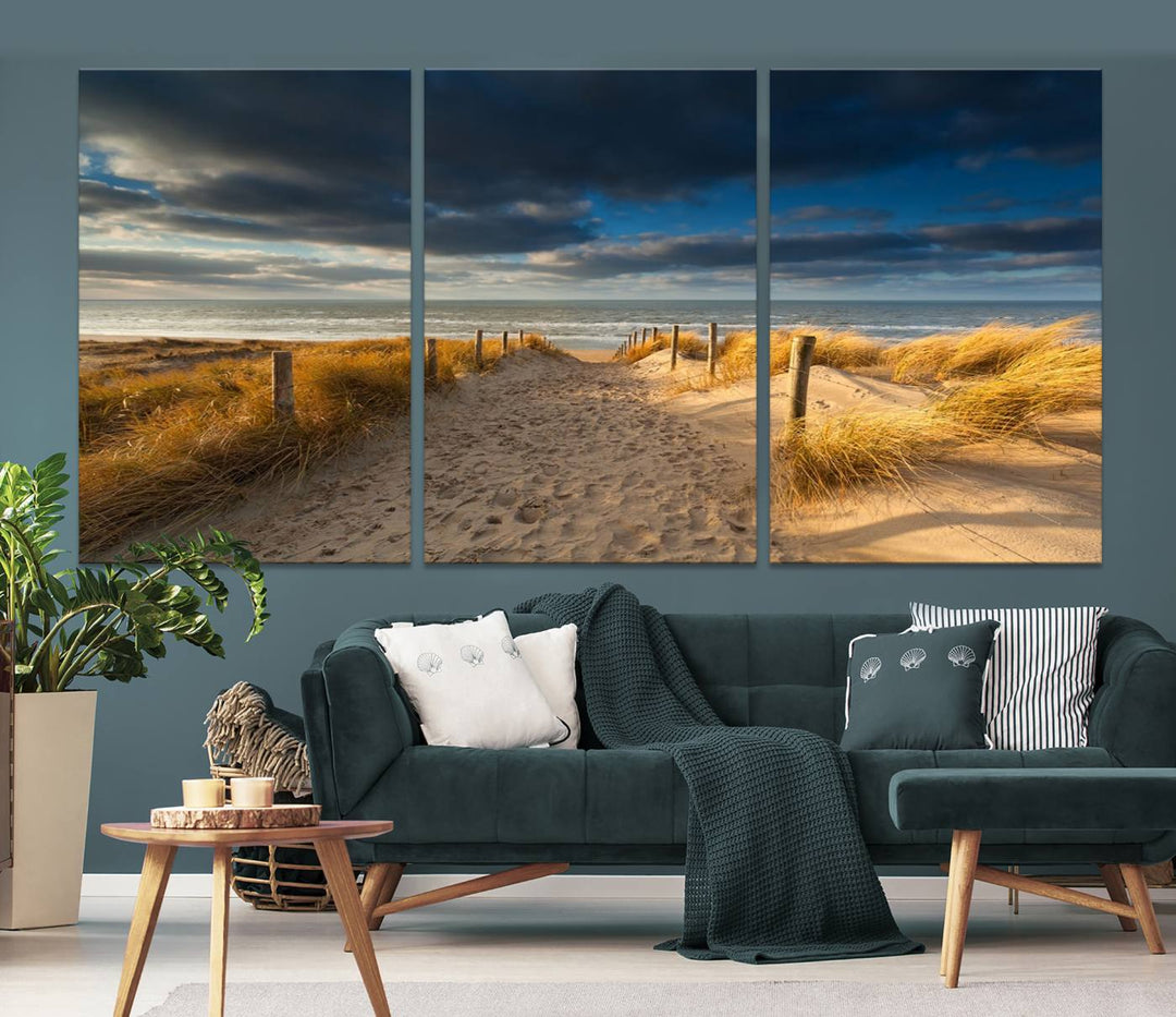 The Ocean Beach Dark Clouds Wall Art Canvas Print is a breathtaking triptych depicting a sandy beach path with tall grasses under an intense cloudy sky. It is crafted on museum-quality canvas with UV protection.